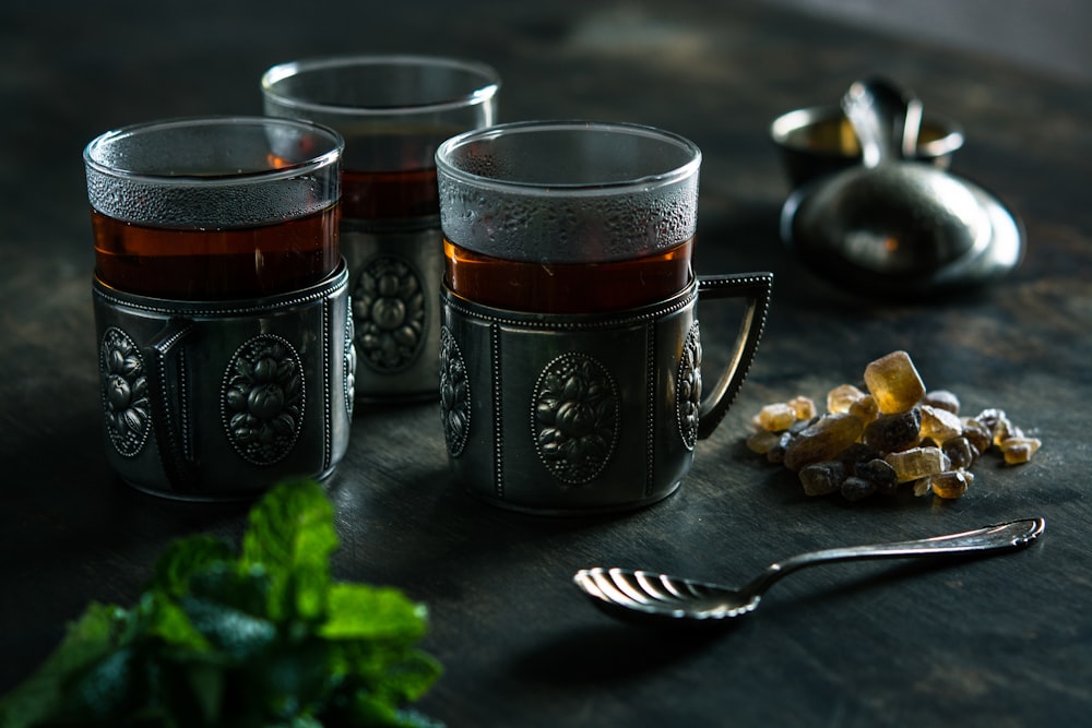 trois tasses en verre transparent avec un liquide brun