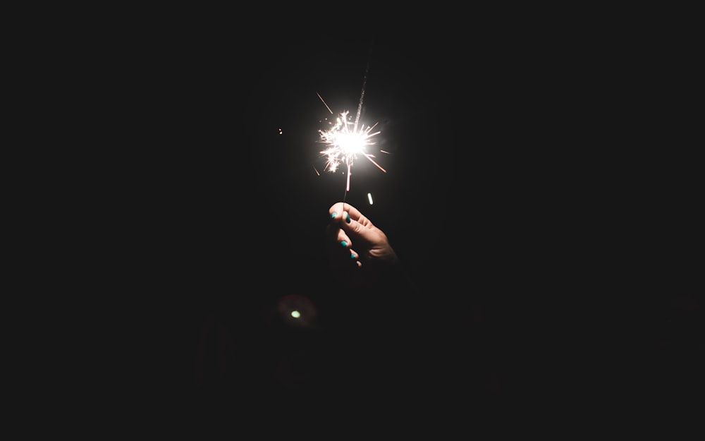 person holding sparkler at night