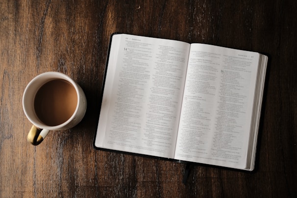 An open Bible with a warm cup of tea beside it.