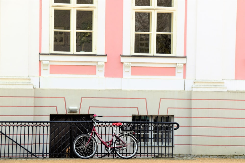 red bicycle parked in front of a pink and white building
