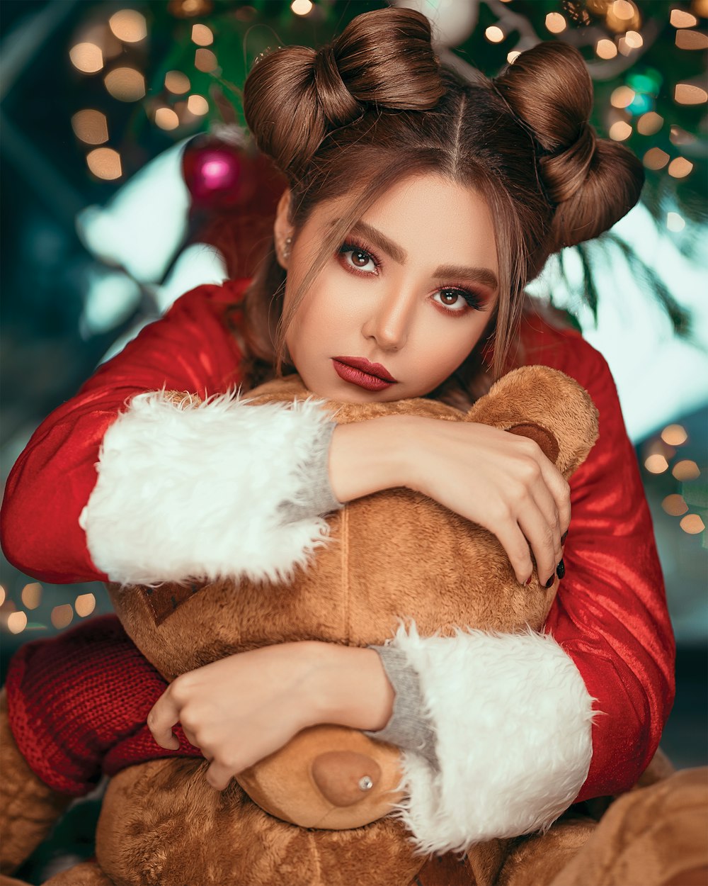 woman wearing red and white Santa costume hugging brown bear plush toy