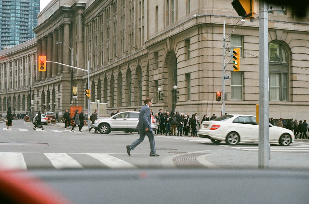 man in gray suit jacket and dress pants crossing pedestrian