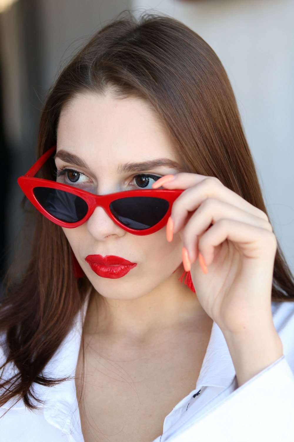 woman in white top about to wear off her red sunglasses