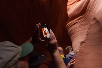 man in gray and green fitted cap taking photo of cave