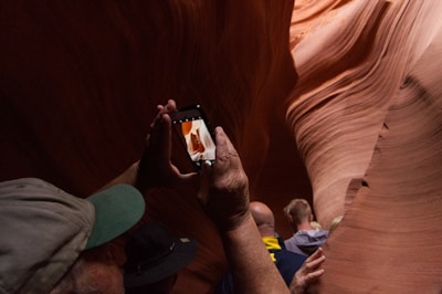 man in gray and green fitted cap taking photo of cave