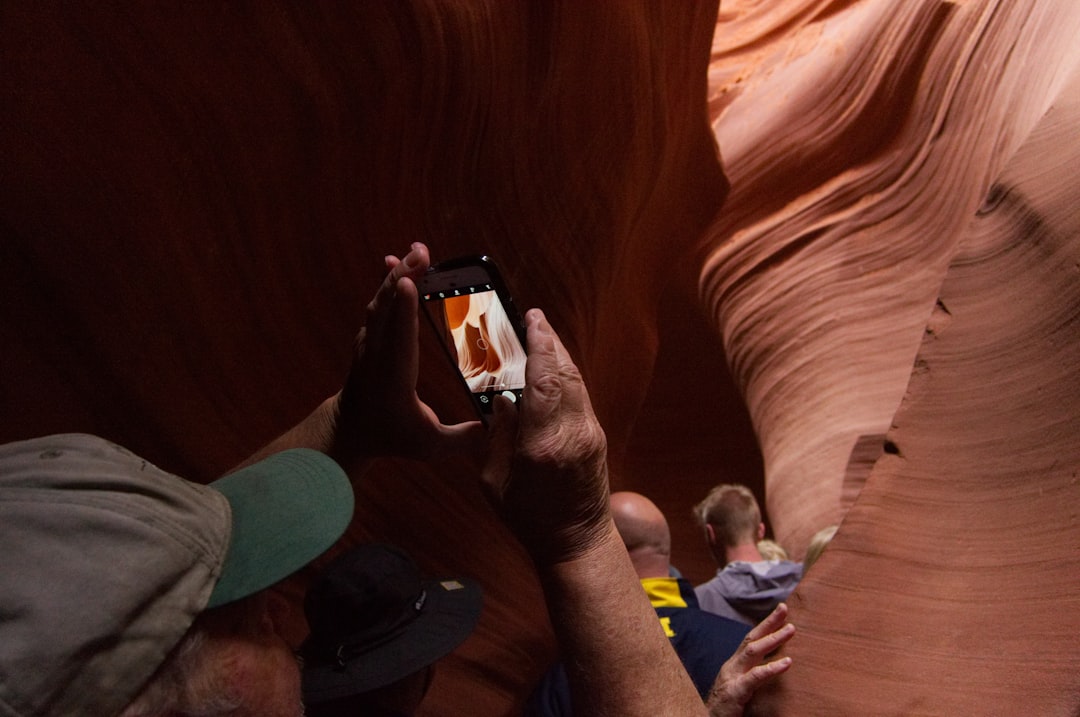 man in gray and green fitted cap taking photo of cave,