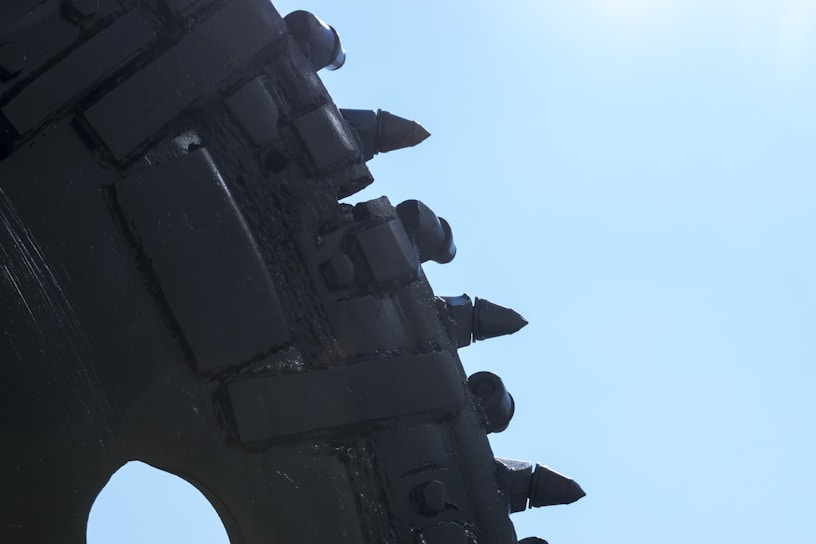 A close-up of heavy-duty drilling equipment operating on an oil field under a clear blue sky.