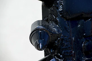 A close-up of a high-speed machine crafting a shiny metal car part in a bright factory.