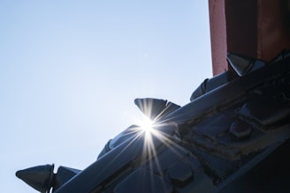 Close-up of metal anti-bird spikes installed along a building ledge with a clear blue sky background.