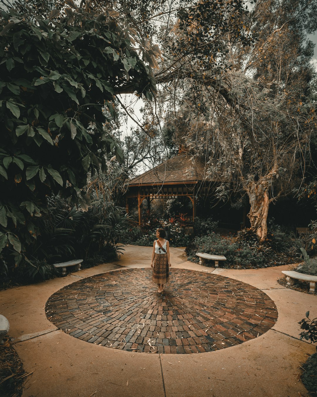  woman wearing skirt standing between empty benches during daytime courtyard forecourt