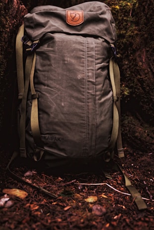 A weathered leather backpack with the elephantin’ logo embossed, resting against a tree trunk.