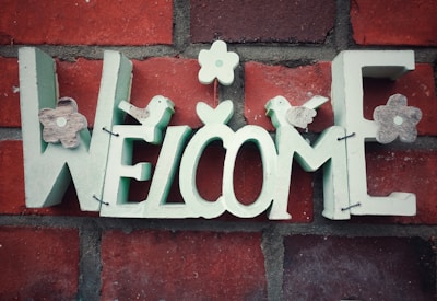 A charming hand-painted sign reading 'Welcome to the Painted Cottage' hanging on a rustic door.