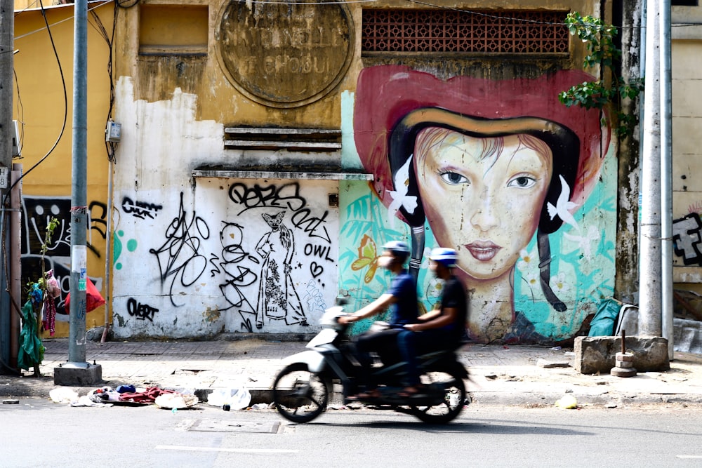 men riding motorcycle near wall with paints