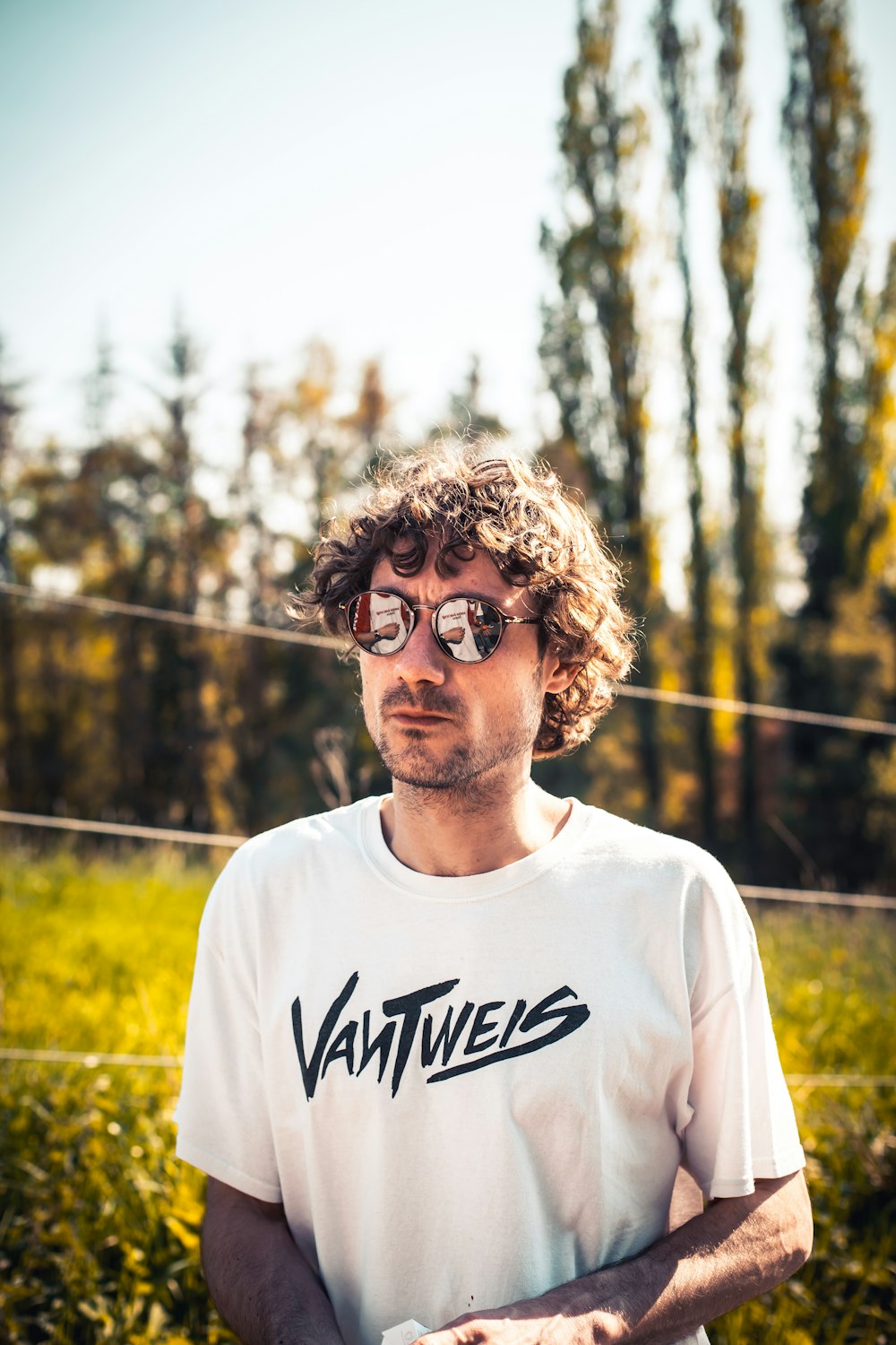 man in white Vantweis t-shirt and gold-framed sunglasses