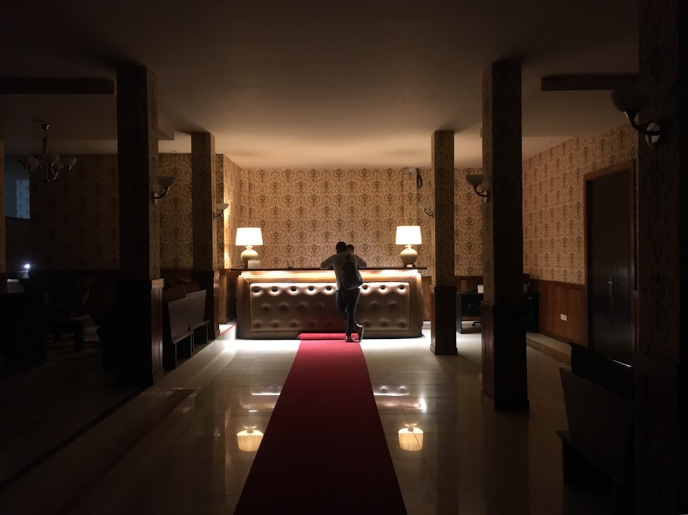 a man standing on a red carpet in a hotel lobby