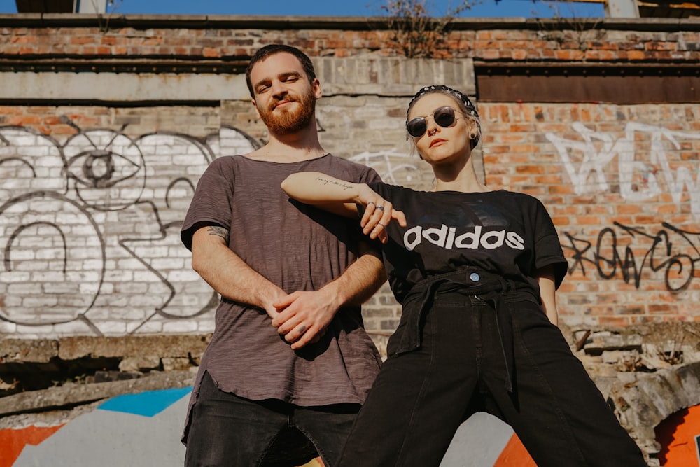 woman putting her elbow on man chest while standing near wall