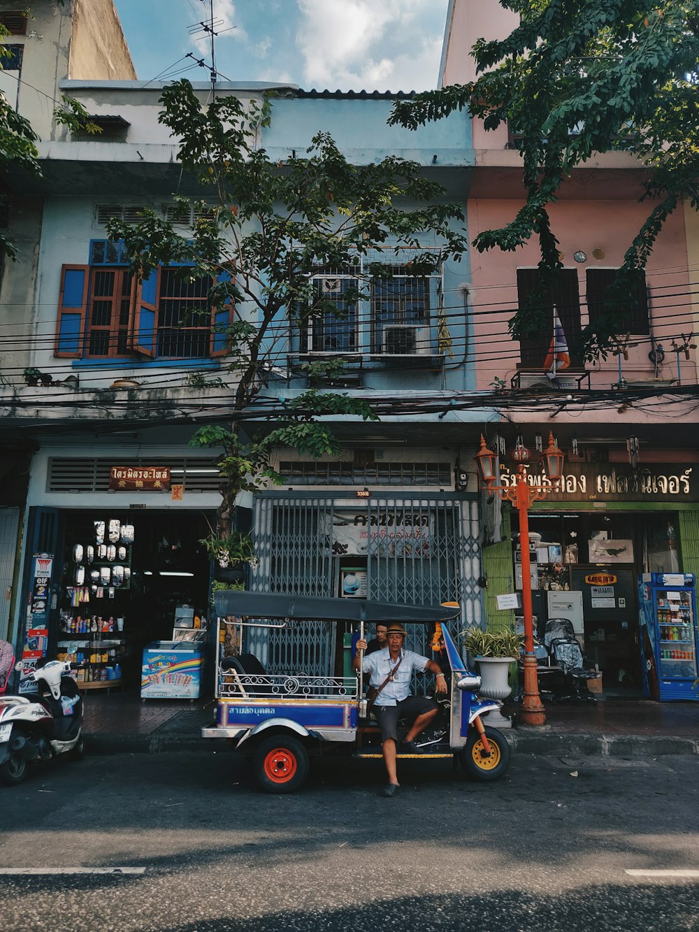 man sitting on auto rickshaw parked beside house
