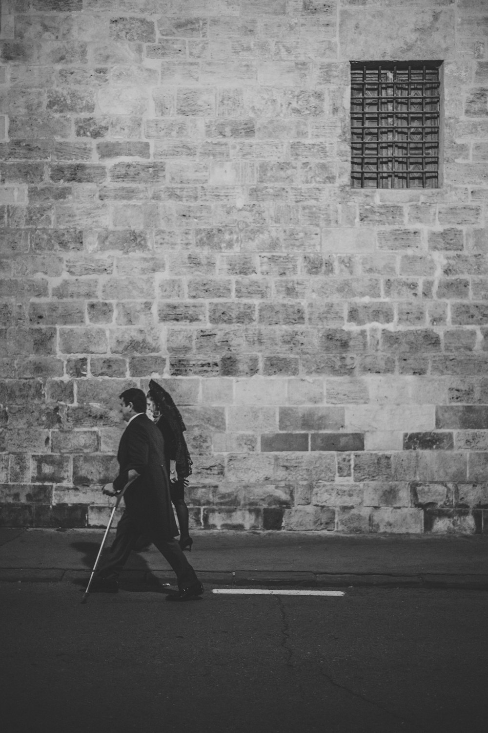grayscale photo of man walking near wall