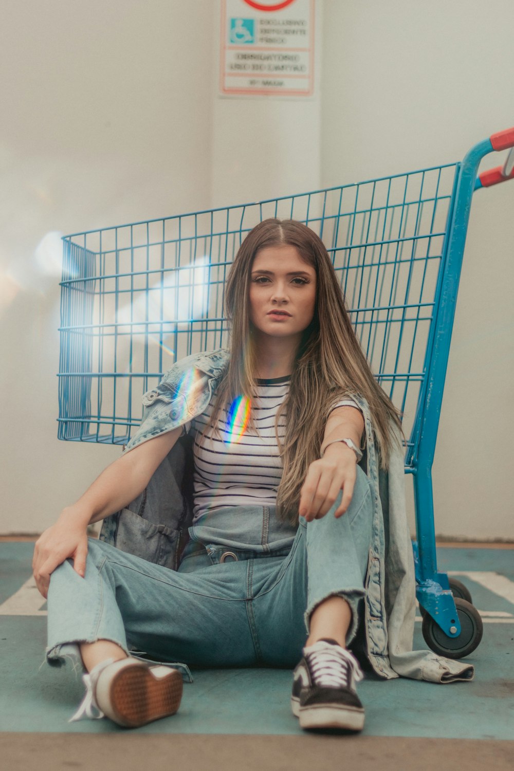 woman in grey shirt and green denim jeans sitting beside shopping cart