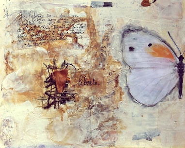 A mixed media artwork featuring handwritten text in French and a collage with earthy textures. A large butterfly with light-colored wings, accented with orange and black spots, occupies the right side. The word 'liberté' is written in cursive near a heart shape surrounded by textured materials.