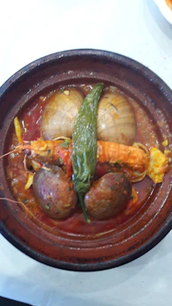 A colorful plate of traditional Spanish stew served in a rustic ceramic dish.