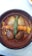 A rustic clay dish containing a seafood stew with large clams, a langoustine, potatoes, and a green chili pepper in a red sauce.