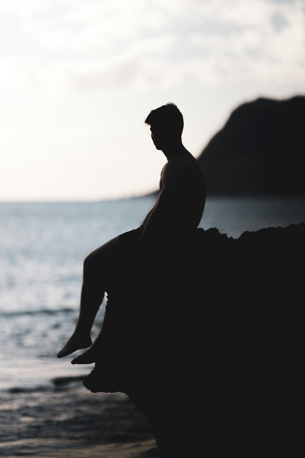 silhouette photography of man siting on a cliff