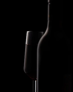 Cinematic shot of a bottle of fine wine and crystal glass with deep shadows and warm lighting