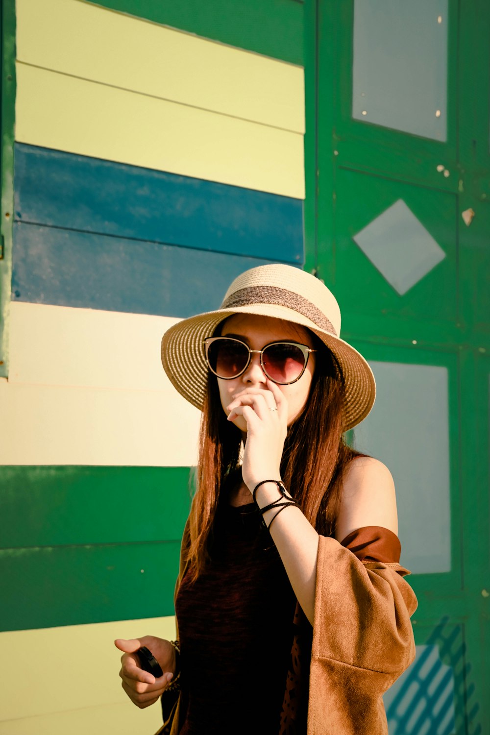 Femme en robe noire avec cardigan marron portant un chapeau en osier marron