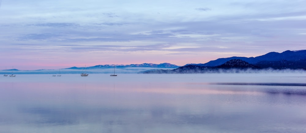 boats on body of water near mountain during daytime