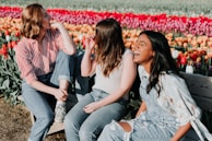 three women sitting wooden bench by the tulip flower field