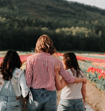 three women walking along field of tulip flowers