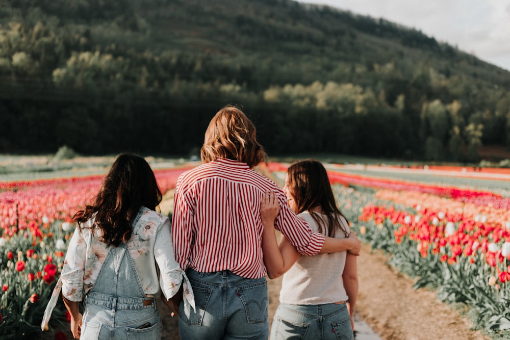 Drei Frauen spazieren entlang eines Tulpenblumenfeldes