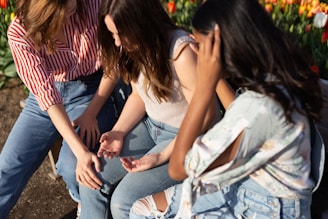 three woman sitting at each other near flowers