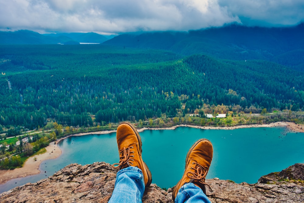 man sitting on cliff overlooking city