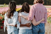 three women holding hand in front of flower garden