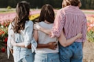 three women holding hand in front of flower garden