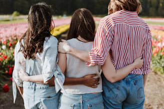 three women holding hand in front of flower garden