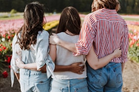 three women holding hand in front of flower garden