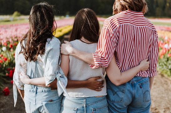three women holding hand in front of flower garden