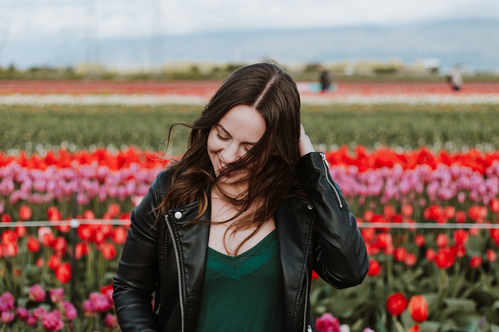 woman in black leather jacket with one hand on hair outdoors