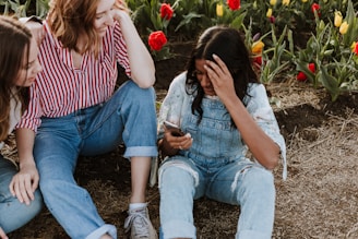 Girls planting flowers together in a sunny garden area.