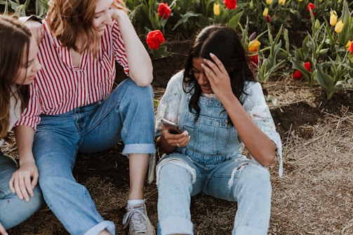Girls planting flowers together in a sunny garden area.