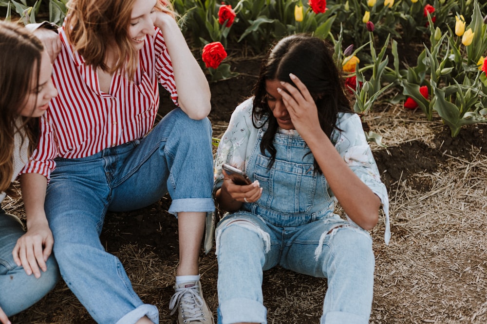 Drei Frauen lachen, während sie in der Nähe von Blumen sitzen