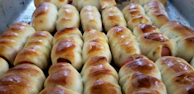 Golden-brown sausage rolls fresh from the oven, flaky and inviting on a ceramic plate.
