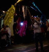 Group of children joyfully breaking a bright piñata at a festive outdoor party.