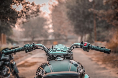 A close-up of hands gripping motorbike handles with forested hills in the background.