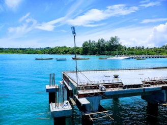 Engineers inspecting a waterfront pier structure with calm water and boats in the background.