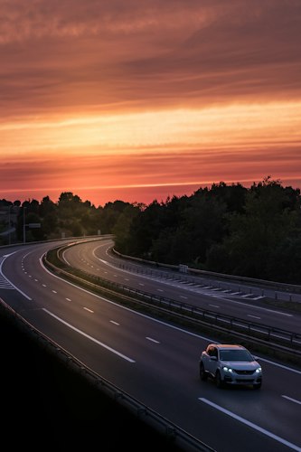 A rental car parked at a roadside pull-off with a scenic view in the background
