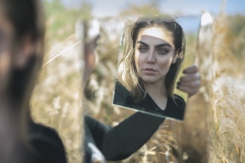 woman in black shirt looking at herself in the mirror